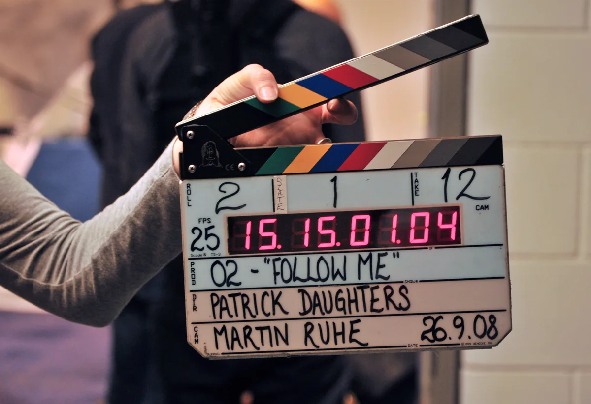 A black-and-white film clapperboard held open on a production set