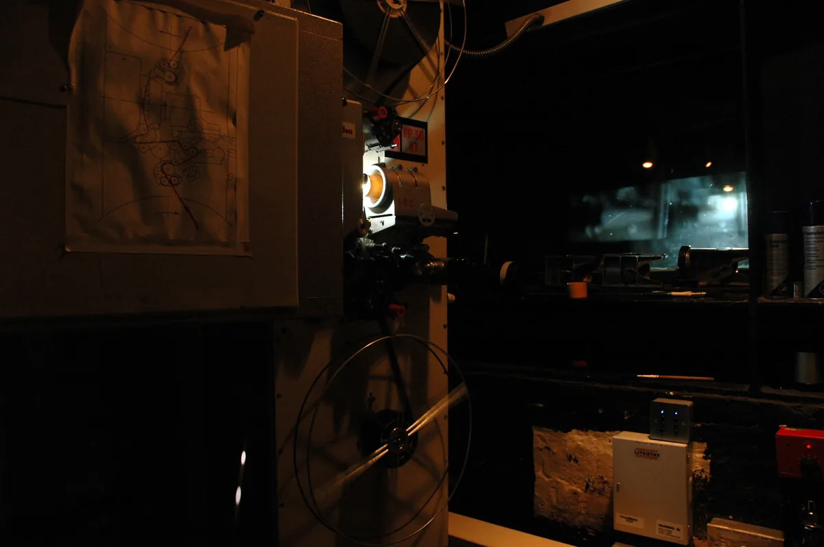 A vintage cinema film projector running with reels in a projection booth